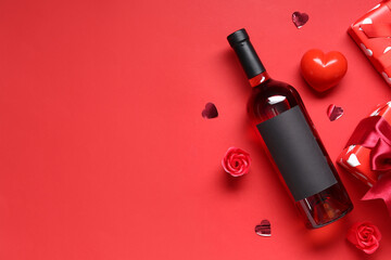 Bottle of wine with gifts and decor on red background. Valentine's Day celebration