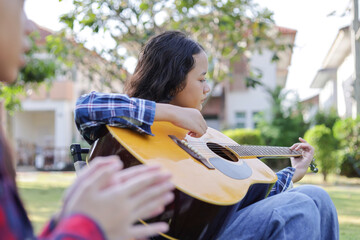 Asian kid girl and friend playing guitar and singing in park