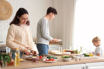 Young woman with her husband and little son cutting lime for Fajita in kitchen