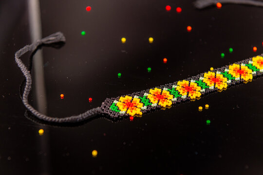 Black, green, yellow, orange and red beaded necklace on black background, Lesya Ukrainka like DIY