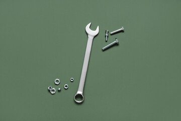 Wrench with tap bolts and chrome nuts on green background