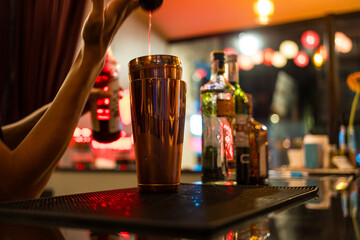 A detailed shot of a bartender expertly pouring a cocktail into a glass.
