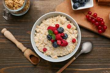 Composition with tasty oatmeal and berries on wooden background