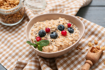 Napkin, bowl with tasty oatmeal, chia seeds and berries on grey wooden background
