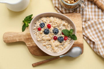 Composition with napkin, tasty oatmeal and berries on beige background