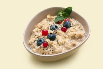 Bowl with tasty oatmeal, chia seeds and berries on beige background