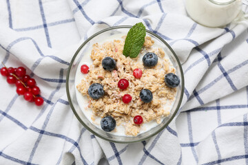 Bowl with tasty oatmeal and berries on napkin as background