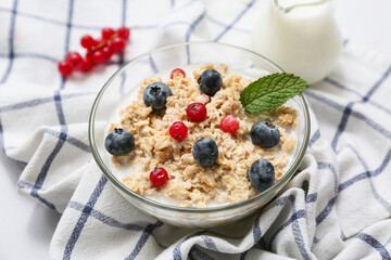 Bowl with tasty oatmeal and berries on napkin as background, closeup