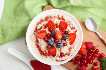 Bowl with tasty oatmeal with berries on white background
