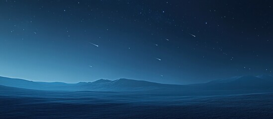 Night sky with shooting stars over a dark, mountainous landscape.