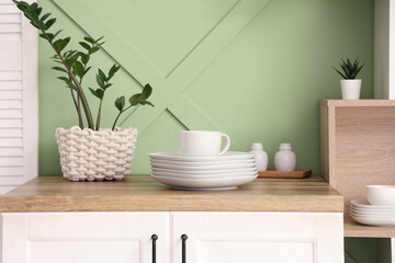 Clean plates and cup on wooden counter in kitchen, closeup