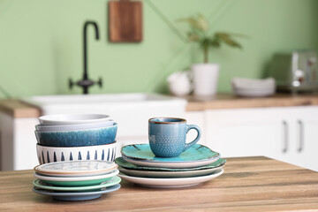 Clean plates, bowls and cup on wooden counter in kitchen, closeup