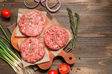 Cutting board with tasty meat cutlets on wooden background