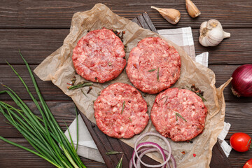 Tray with raw meat cutlets with spices on wooden background