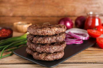Tray with tasty meat cutlets on wooden background