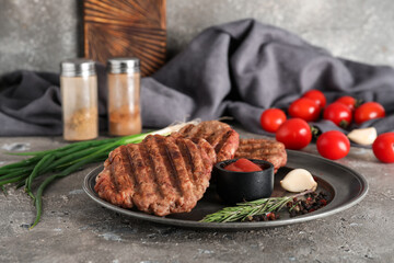 Plate with tasty meat cutlets and rosemary on grey grunge background
