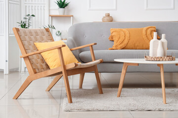 Interior of stylish living room with cozy wooden armchair, grey sofa and coffee table