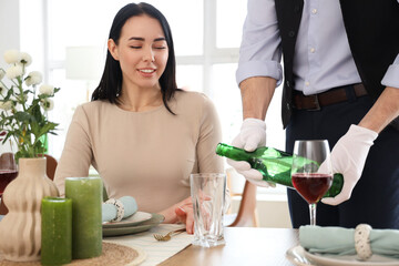 Male waiter pouring water for woman at table in restaurant