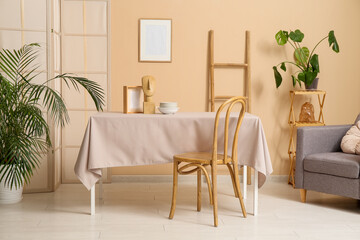 Dishes with decor on beige tablecloth in dining room interior