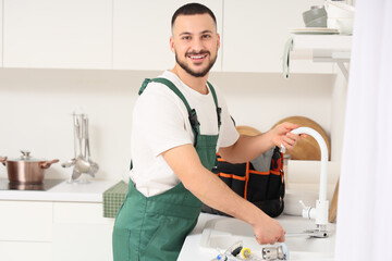 Male plumber cleaning clogged pipe in kitchen