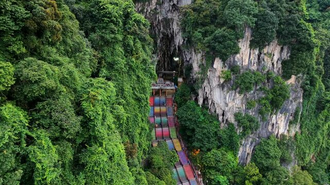 Batu Caves in Malaysia drone video pushing in to reveal the iconic temple cave entrance at the top of rainbow stairs