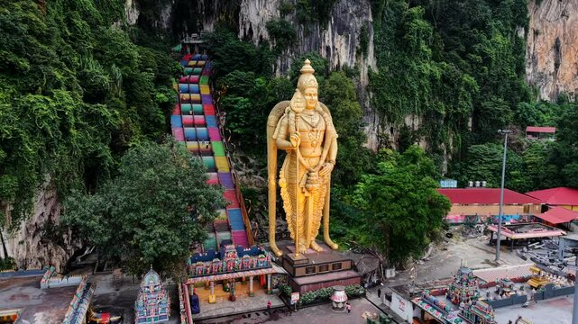 Batu Caves stock drone video of temple outside of Kuala Lumpur, Malaysia with 43m tall Murugan statue next to rainbow stairs