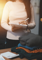 Obraz premium Startup SME small business entrepreneur of freelance Asian woman wearing apron using laptop and box to receive and review orders online to prepare to pack sell to customers, online sme business ideas.