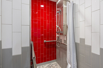 New single, private, gym locker room shower with red tile wall, bench, tile floor, and white shower curtain.