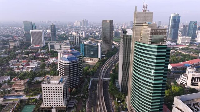 Drone video of light rail train traveling between buildings in Sudirman Central Business District of Jakarta, Indonesia