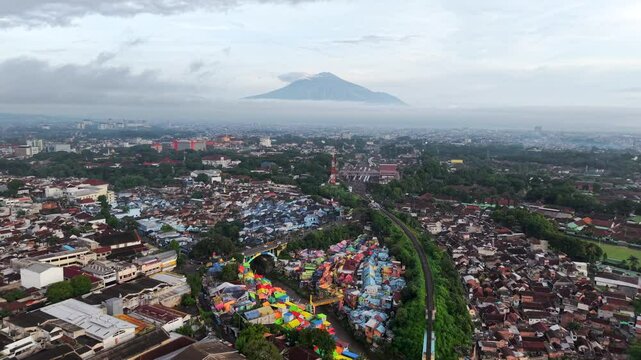 Malang, Java, Indonesia stock drone video - Aerial footage of the city of Malang on the Indonesian island of Java with the Rainbow Village and a volcano in the distance 