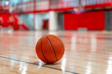 Close up photo of a basketball on a new hardwood gym, court, floor with a blurry background.
