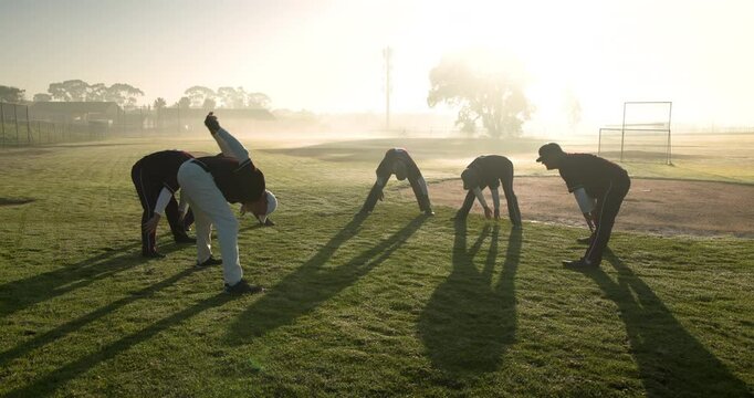 Baseball players stretching on field during early morning practice session