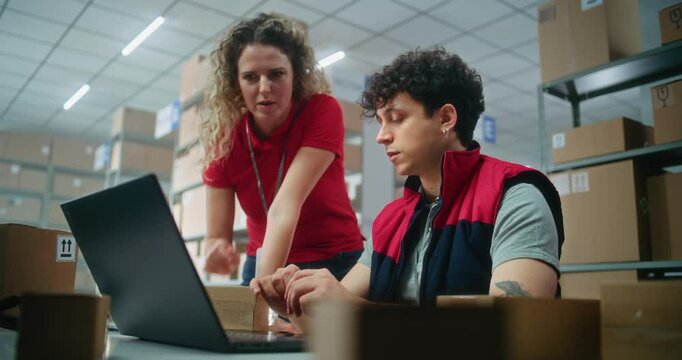 Two warehouse workers or logistics specialists scan parcel with scanner, prepare order for shipping to client, check information on laptop computer, work in post office. Online store delivery service.