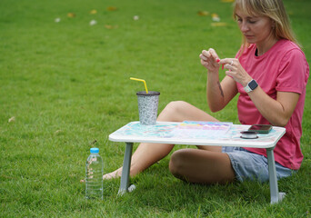 Young woman beading colorful bracelets outdoors in a park