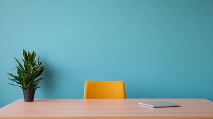Minimalist home office with wooden desk, yellow chair and closed laptop against turquoise wall