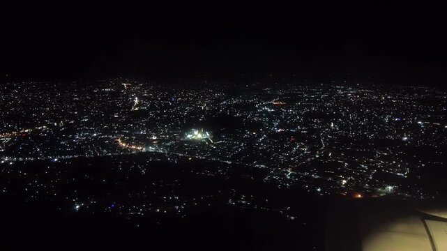 Near midnight of New Year's Eve, scattered fireworks and firecrackers sparkle on the ground as viewed from aircraft approaching Ninoy Aquino International Airport, Metro Manila, Philippines.
