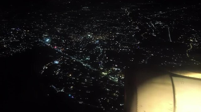 Near midnight of New Year's Eve, scattered fireworks and firecrackers sparkle on the ground as viewed from aircraft approaching Ninoy Aquino International Airport, Metro Manila, Philippines.
