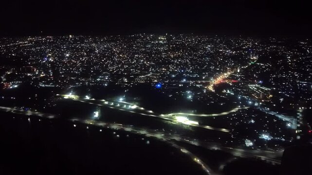Near midnight of New Year's Eve, scattered fireworks and firecrackers sparkle on the ground as viewed from aircraft approaching Ninoy Aquino International Airport, Metro Manila, Philippines.