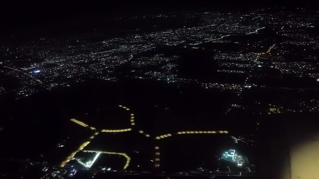 Near midnight of New Year's Eve, scattered fireworks and firecrackers sparkle on the ground as viewed from aircraft approaching Ninoy Aquino International Airport, Metro Manila, Philippines.