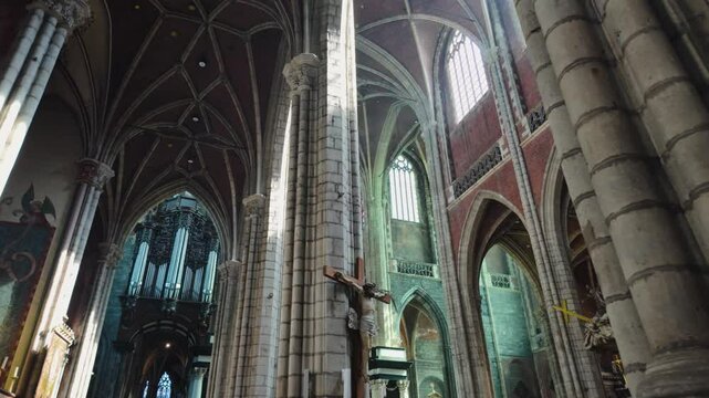 POV of interior of Saint Bavo's Cathedral in Ghent, featuring monumental Gothic architecture, intricate details, and serene religious ambiance bathed in natural light.