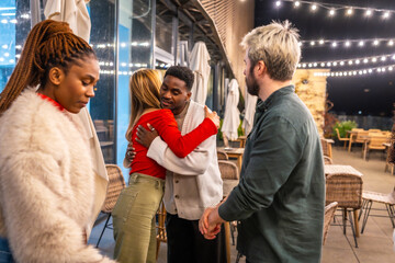 Friends saying goodbye on a terrace at night