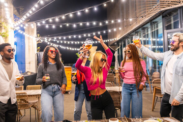 Sensual blonde woman dancing with friends at outdoors night party