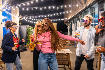 African woman dancing with multi-ethnic friends at night party outdoors