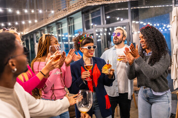 Friends clasping and singing birthday song to a woman