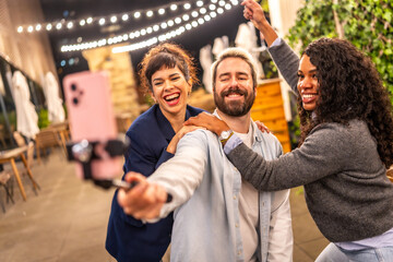 Man recording online video blog with friends at night party