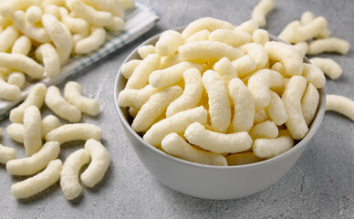 Crunchy corn snacks in a ceramic plate on a gray background.