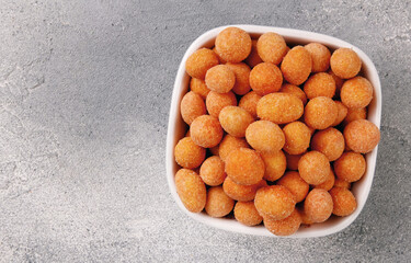 Spicy coated fried peanuts on gray background. Snacks and nuts.