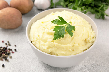 Mashed potatoes in white bowl on grey concrete background. Healthy food