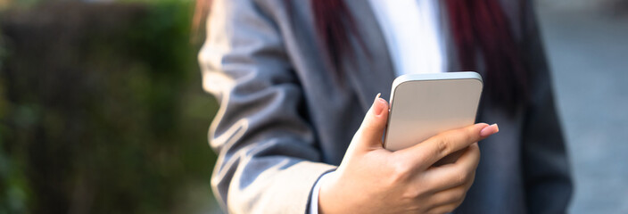 Female business office worker holding phone, outdoors