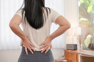 asian woman having low back pain and spinal compression. adult female with muscle pain after waking up.